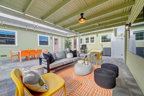 A covered patio area with a sofa, chairs, and a dining table. - AvoCottage – 1920s Themed Cottage near Disneyland, Pool & Game Room, Sleeps 12 (Santa Ana)