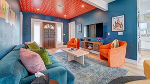 A living room with a blue wall, a red ceiling, and orange chairs. - Magical Stay Near Disneyland with Pool & Fire Pit (Santa Ana)