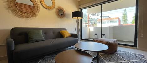 Una sala de estar moderna con un sofá, dos mesitas y espejos decorativos en la pared.