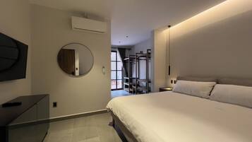 Een moderne hotelkamer met een groot bed, een ronde spiegel, een flatscreen televisie en een ingebouwde airconditioning.