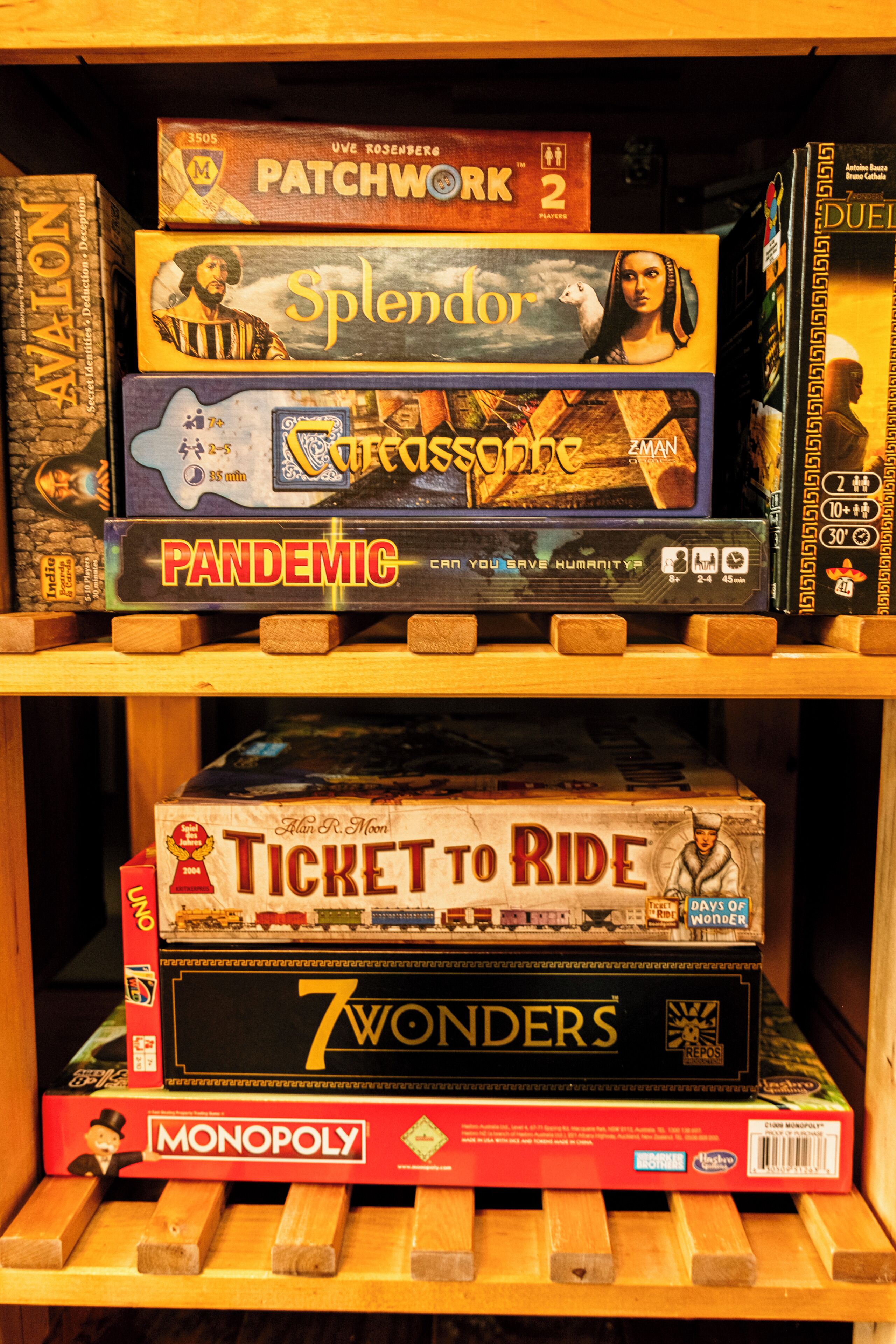 A shelf with various board games, including 'Patchwork 2', 'Splendor', '7 Wonders', 'Ticket to Ride', and 'Monopoly'.