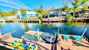 A dock with chairs and a boat, a pier with a building, and a calm water body. - Charming 2/2 waterfront farm home with tons of TV stations, WiFi, dock, & more (Spring Hill)