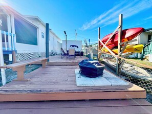 A wooden deck with a bench and a kayak storage area. - Charming 2/2 waterfront farm home with tons of TV stations, WiFi, dock, & more (Spring Hill)