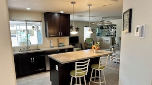 A modern kitchen with dark cabinets, a granite countertop, and a central island with bar stools.
