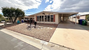 A building with a covered entrance, a patio area with a cactus garden, and a clear sky.