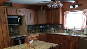 A kitchen with wooden cabinets, a granite countertop, a built-in oven, a coffee maker, and a sink. - Charming Country farmhouse (Fredonia)