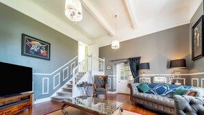 A living room with a TV, a glass coffee table, a sofa, and a staircase leading to another room. - 3 bedroom accommodation in Annan (Annan)