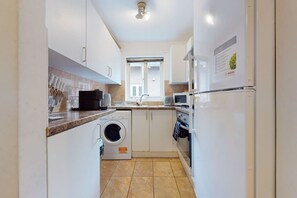 Compact kitchen with a window above the sink, a washing machine, and a microwave.