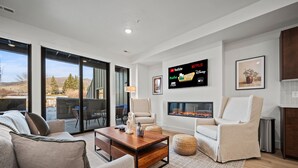 A modern living room with a fireplace, comfortable seating, and a large TV displaying streaming services.