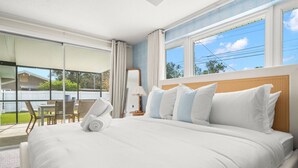 Een hotelkamer met een groot bed, een balkon met uitzicht en een eethoek met stoelen en een tafel.
