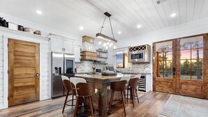 A spacious kitchen with a large island, bar stools, a built-in oven, and a microwave. - Diamond Sunset Retreat w/ Seasonal Pool, Hot Tub, Game Room & Outdoor Spaces! (Broken Bow)