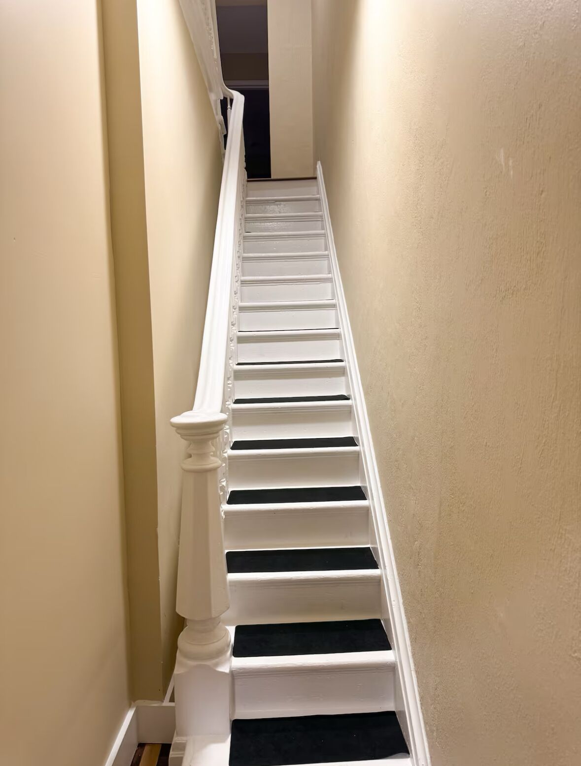 A staircase with white balusters and a beige wall.