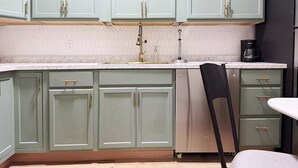 A kitchen with light green cabinets, a white countertop, and a black chair. - The Cardinal 808 B - KING 1BR-1BA Apt
 (Evansville)