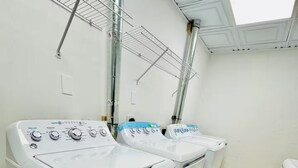 A laundry room with two front-loading washing machines and a drying rack. - The Cardinal 808 B - KING 1BR-1BA Apt
 (Evansville)