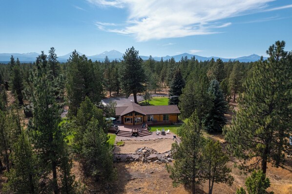 A lodge with a deck, outdoor seating, and a view of mountains.