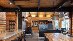 Ein Holzblockhaus-Interieur mit einer Holztresore, einer Sitzgelegenheit und einem großen Fenster mit Bergblick.