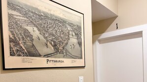Un mapa histórico de Pittsburgh enmarcado en una pared, una puerta blanca con pomo negro y un interruptor de luz.