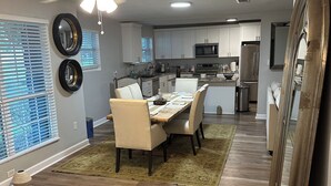 A modern kitchen with white cabinets, a central island, and a dining area with a table and chairs.