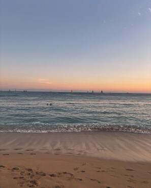 A beach with footprints in the sand and a calm sea with sailboats in the distance. - Sip And Sea  (Bradenton)