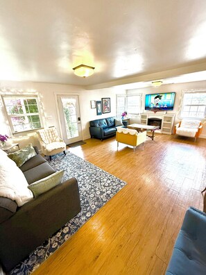 A living room with a sofa, armchairs, a coffee table, a TV, and a fireplace. - Midtown Retreat, Spacious, Silkie Petting Zoo, WiFi, 5 Star (Sacramento)