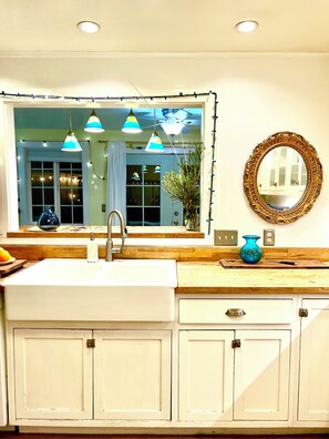 A kitchen with a large window, pendant lights, a sink, cabinets, and a mirror. - Midtown Retreat, Spacious, Silkie Petting Zoo, WiFi, 5 Star (Sacramento)