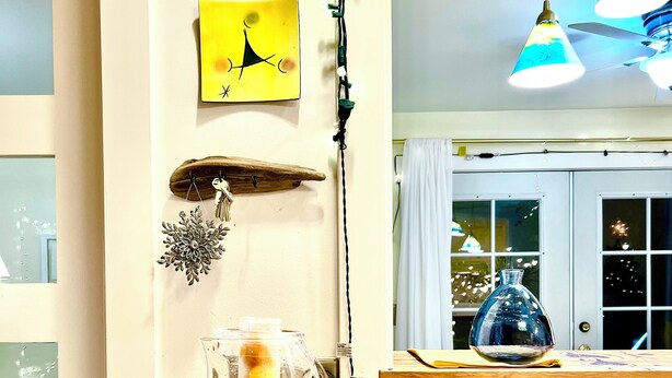 Un comptoir de cuisine avec une carafe d’eau, une assiette de citrons et une décoration murale.