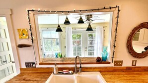 Une cuisine dotée d’un évier à deux bacs, d’un plan de travail en bois et de meubles de rangement blancs.