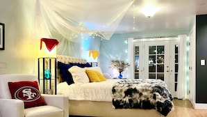 Une chambre à coucher comprenant un lit, une chaise, une table de chevet et une commode.