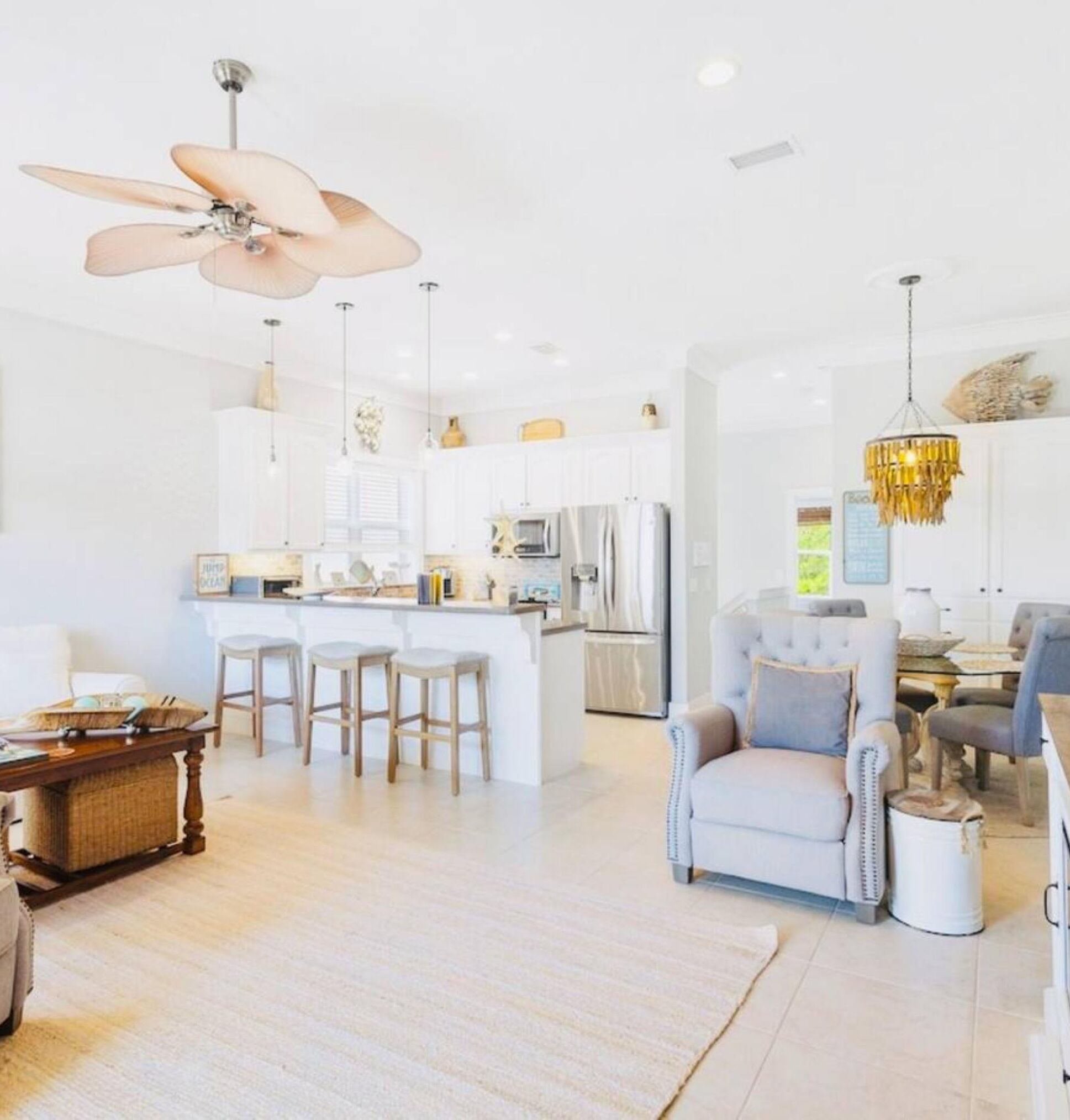 A modern kitchen with white cabinets, a central island with stools, stainless steel appliances, and pendant lighting.