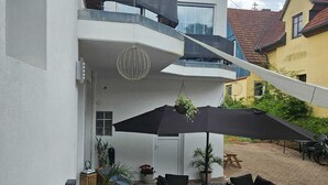 A modern two-story building with a patio area featuring outdoor furniture and umbrellas. - Guesthouse Schindhard (Schindhard)