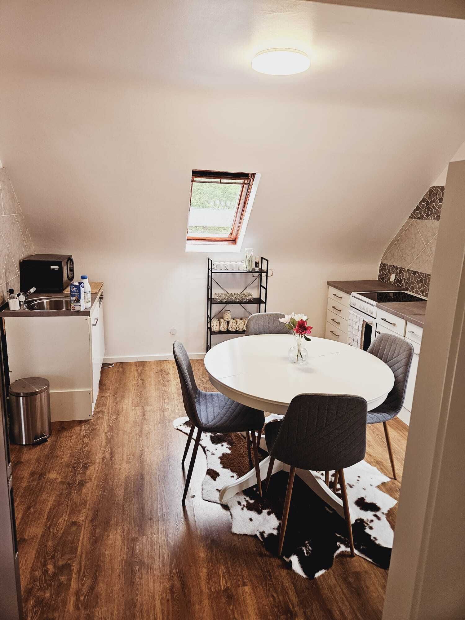 A compact kitchen with a round dining table, a built-in oven, and a window above the sink.