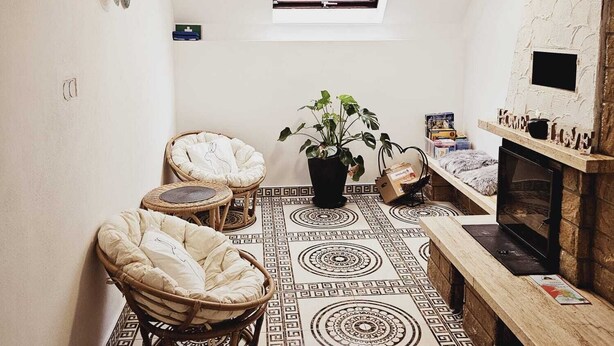A cozy room with a high ceiling, a skylight, a fireplace, and a patterned floor. - Guesthouse Schindhard (Schindhard)