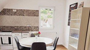 A modern kitchen with a round dining table, two chairs, a cowhide rug, and a glass cabinet. - Guesthouse Schindhard (Schindhard)