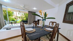 Un comedor con una mesa negra, sillas de madera y un jarrón con flores amarillas.