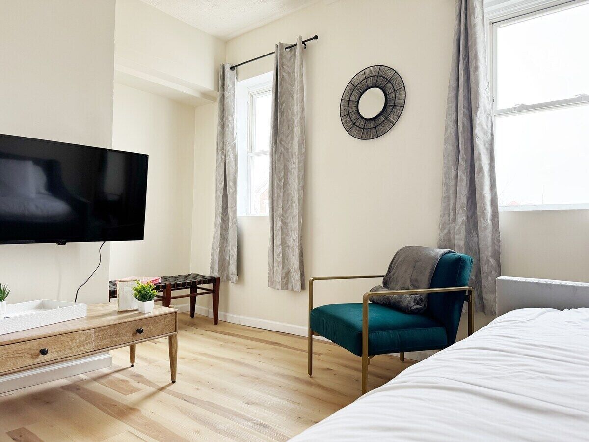 A modern bedroom with a bed, a TV, a desk with a plant, and a chair.