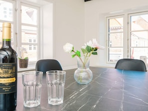 A table with a bottle of wine, two glasses, and a vase with flowers. - 2 Person Holiday Home in Ringkobing (Ringkobing)