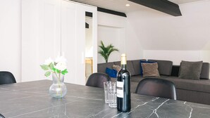 A modern living room with a marble table, a bottle of wine, and a vase of flowers. - 2 Person Holiday Home in Ringkobing (Ringkobing)
