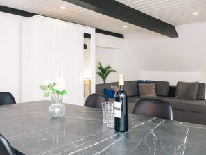 A modern living room with a marble table, a bottle of wine, and a vase of flowers.