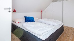 A bedroom with a bed, two red wall lamps, a wardrobe, and a door. - 2 Person Holiday Home in Ringkobing (Ringkobing)