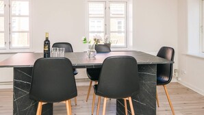 A dining area with a marble table, black chairs, and a bottle of wine. - 2 Person Holiday Home in Ringkobing (Ringkobing)
