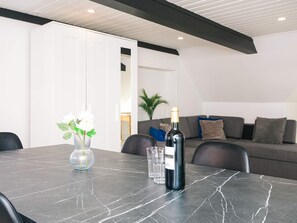 A modern living room with a dark marble table, a bottle of wine, and a vase with flowers.