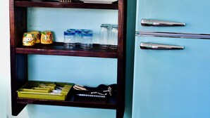 A light blue vintage refrigerator with a built-in wooden shelf unit above it.