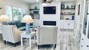 A modern living room with a sofa, two armchairs, a coffee table, and a TV.