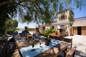 Un espace de restauration en plein air avec un bâtiment en pierre, une table dressée pour deux personnes et une plante en pot.
