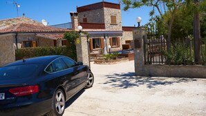 Ein Gebäude aus Stein mit rotem Ziegeldach, ein Auto davor und ein befestigtes Eingangstor.