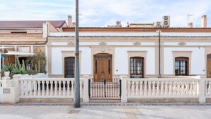 Un edificio con puerta de madera, paredes blancas y un balcón.
