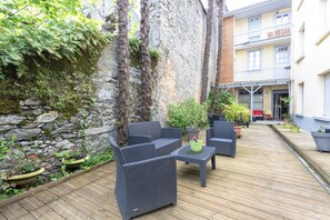 A wooden deck with outdoor furniture, a stone wall, and potted plants.
