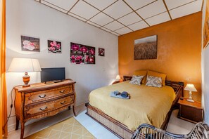 Un dormitorio con cama, cómoda, televisor y una obra de arte en la pared.