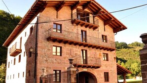 A multi-story stone building with balconies, a stone entrance, and a paved courtyard.
