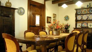 Un'area pranzo con un tavolo di legno, sedie, un vaso con fiori e una mensola con piatti decorativi.